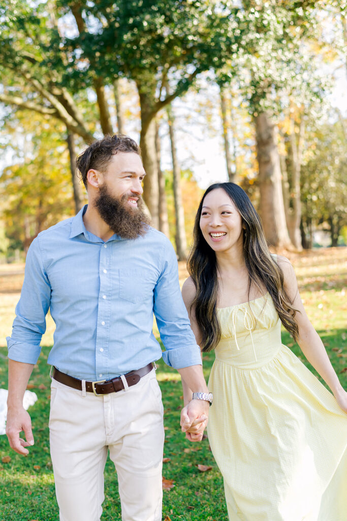 Man in blue collared shirt walking hand in hand with woman in yellow dress