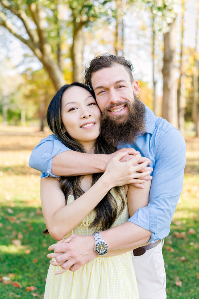 Man in blue smiling at camera while hugging woman in yellow
