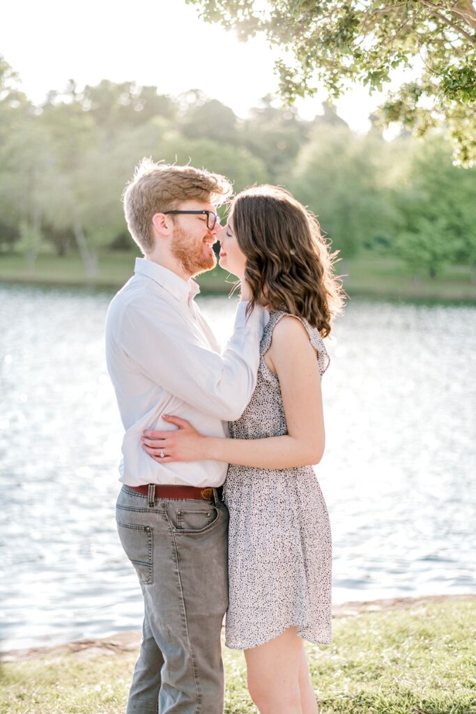 fiances lean in for a kiss in front of the water during furman university engagement session.