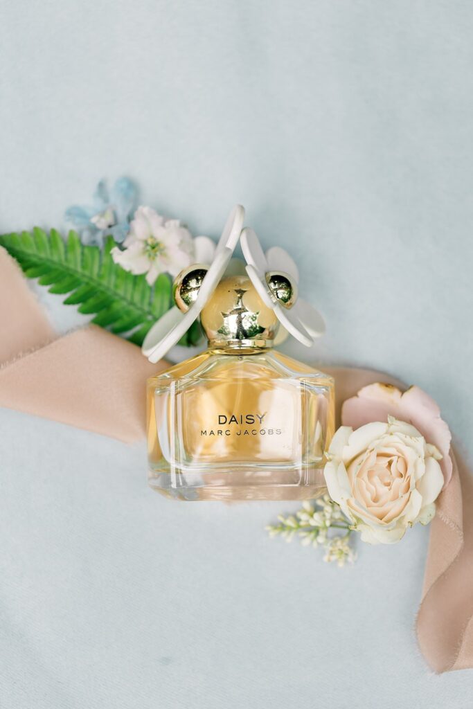 bride's daisy by marc jacobs scent for her Piney Grove Ranch wedding with a blue background and flowers.