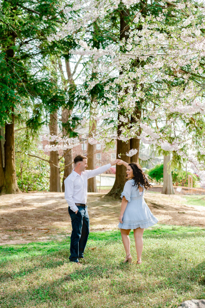 Couple twirling under the cherry blossom trees at Furman University in Greenville SC