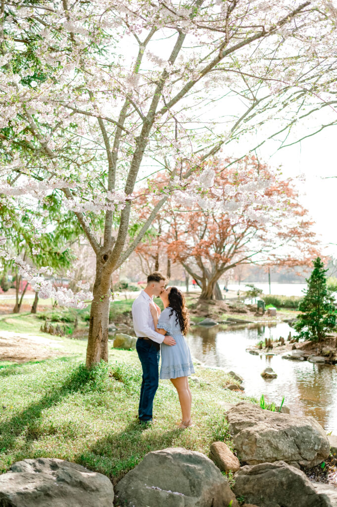 Couple in formal attire sharing a kiss beside the creek near the Furman Lake at Furman University in Greenville SC