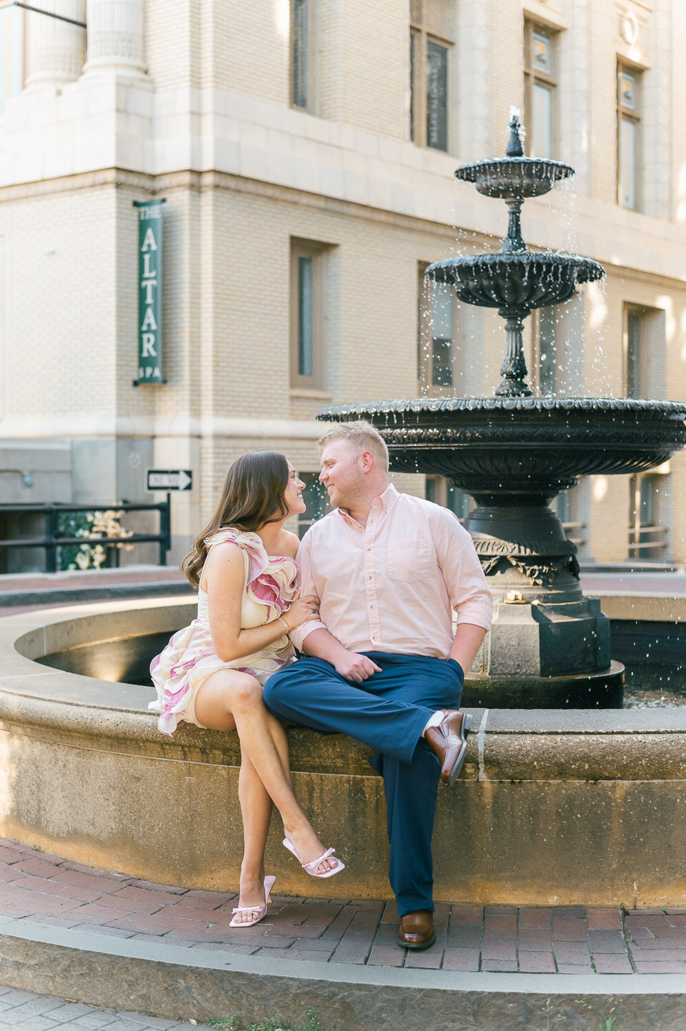 Couple sitting and looking at each other on the fountain outside the Westin Poinsett hotel in Greenville SC