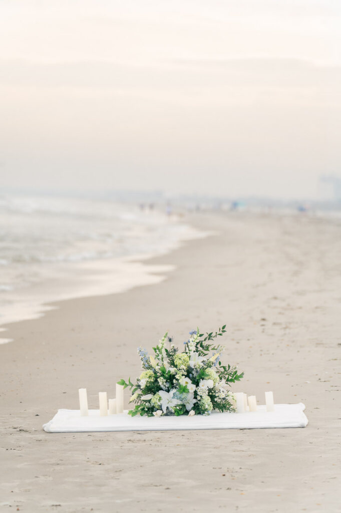 romantic Isle of Palms beach proposal setup with flowers blanket and candles