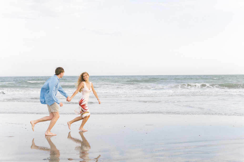 Couple running on the beach for engagement photos at Isle of Palms South Carolina
