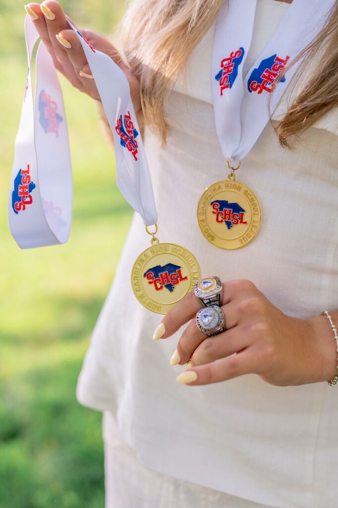High school medals and award rings for senior photographers session in Greenville SC