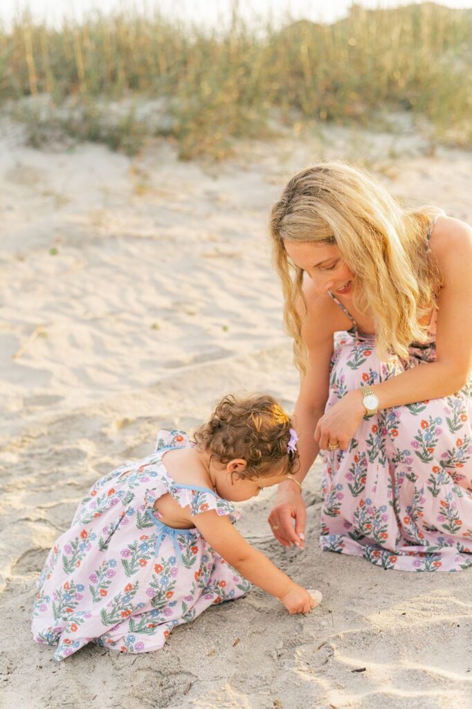 Mom plays with toddler daughter in the sand