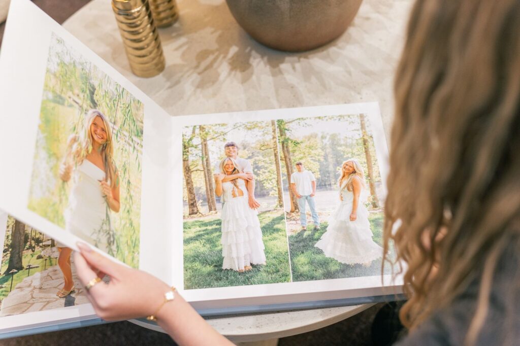 Senior flipping through heirloom album from senior photographers session in Piney Grove Ranch, Greenville SC